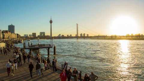 Duesseldorf, NRW Germany - 03 27 2021: Time Lapse Video to Rhein River and Rhein Promenade with lot of Tourists under a beautiful colorful Sunset Sky in Duesseldorf (Düsseldorf) Germany 