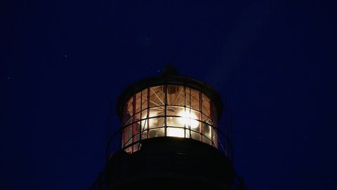 Close up of rotating lamps of Fire Island Lighthouse with moving stars in a night sky