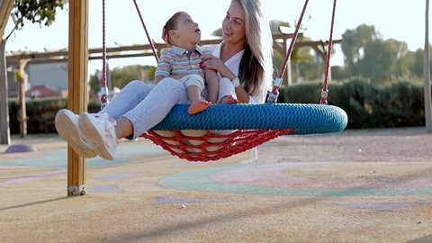 Happy mom proud of her son can walking outdoors. Kid with physical diability. Video of enjoy happy love family outdoors. Lovely mom ride on swing for person with diability with her son. Happy moments