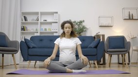 Beautiful expecting woman breathing deeply, practicing yoga at home, meditation
