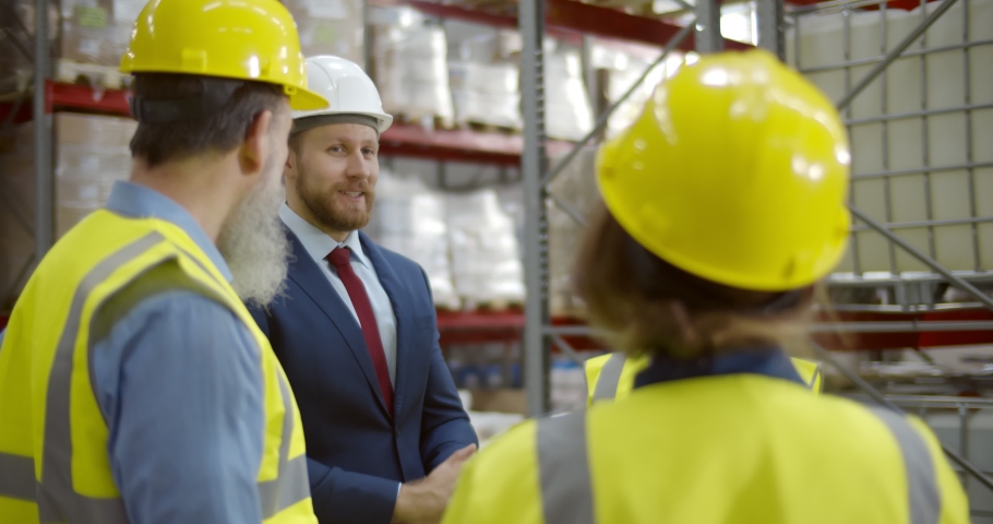 Warehouse owner holding staff meeting discussing successful results. Multiethnic industrial workers during brief meeting applauding standing in large factory storehouse Royalty-Free Stock Footage #1070187421