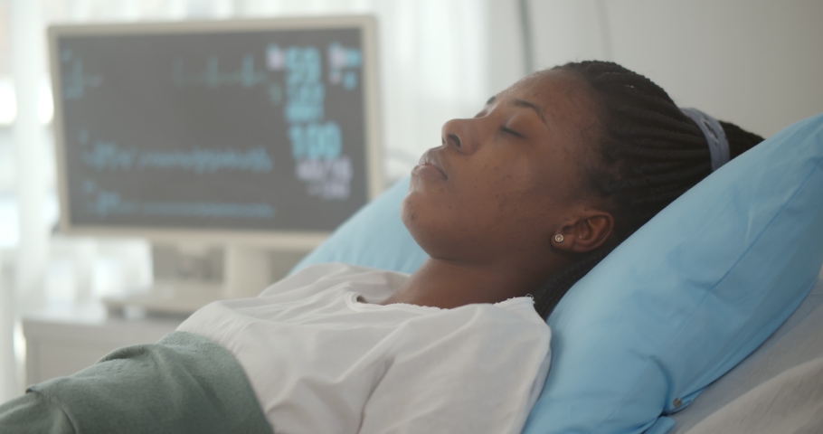 Close up of afro-american patient lying in hospital bed and losing consciousness. African sick woman having heart attack or stroke lying in hospital bed and collapsing Royalty-Free Stock Footage #1070187538