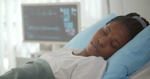 Close up of afro-american patient lying in hospital bed and losing consciousness. African sick woman having heart attack or stroke lying in hospital bed and collapsing