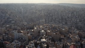 Drone video of the Arab capital Amman Jordan. Houses on the slopes of the mountains with streets, roads and cars at sunset. Aerial view of city life.