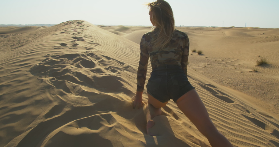 View from the back on a woman pouring out sand from her hand, Rub al Khali, 4k, Go Everywhere