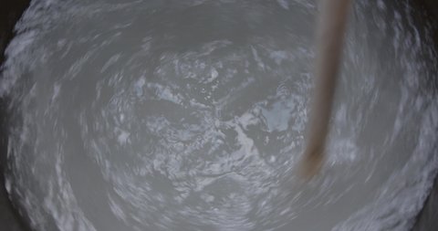 Wooden handle swirls in water mix in a black tank, Blurred moving water spins.