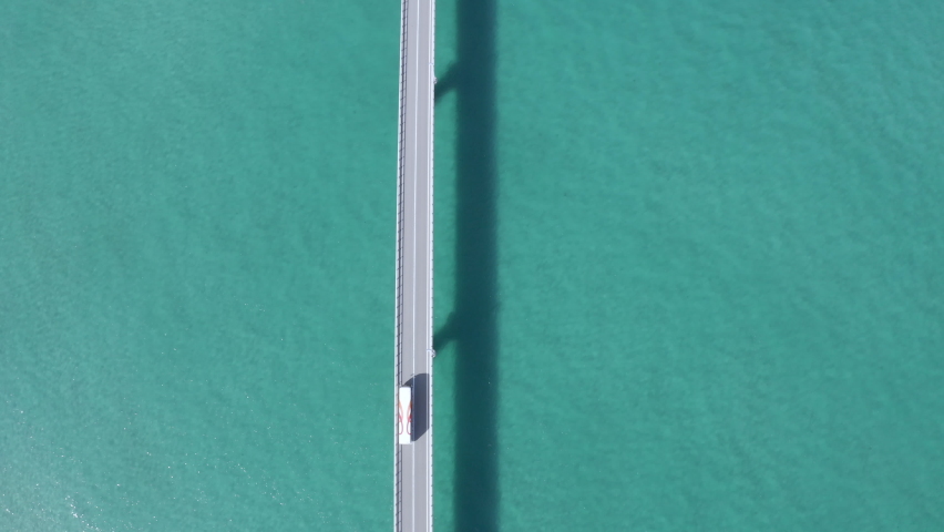 Japan's spectacular spot "Tsunoshima Ohashi" mid-sea road. Take a bird's-eye view from directly above and shoot with a drone while running in parallel. Royalty-Free Stock Footage #1070199373