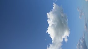 Vertical orientated stock video footage of peaceful cloudy sky. Time lapse of sunny soft white clouds against blue sky background and empty space for your design