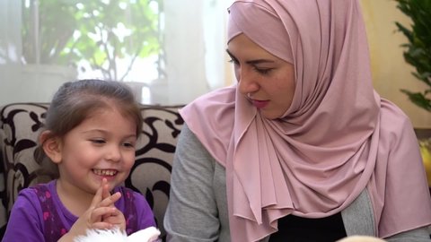 A muslim mother playing with a little dother in toys. Mother and daughter at home together