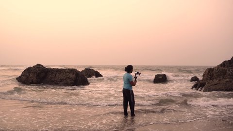 A young and independent filmmaker filming near beach silhouette