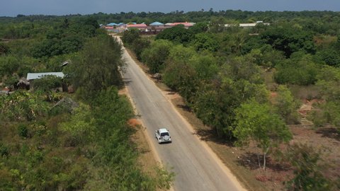Aerial video. The car drives along the African road to the island of Zanzibar in Tanzania, in the frame of the jungle and nature
