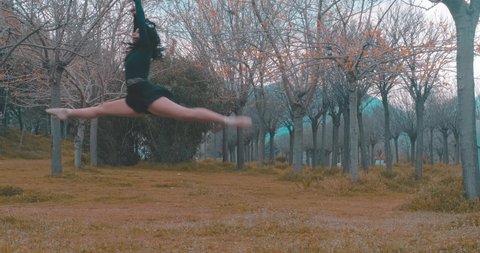 Professional dancer in black dress tutu dances on grass, nature. Ballet, ballerina concept. She's on tiptoes. Beautiful young woman posing, exercising.