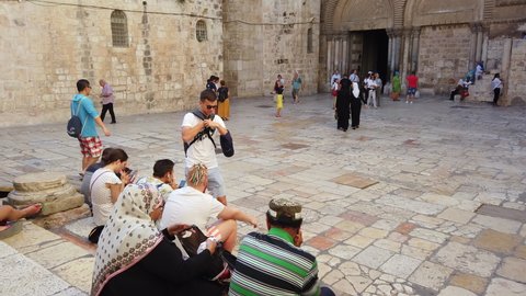 Jerusalem, Israel - July 3, 2019: people resting in the courtyard and entering the Holy Church of the Sepulchre in daytime, 4k video footage