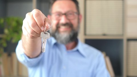 Focus on bunch of keys from house flat apartment in hand of smiling female. Blurred portrait of confident woman professional realtor offering new dwelling real estate unit to potential buyer. Close up