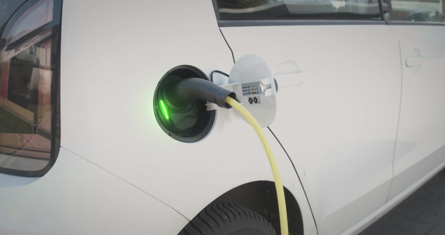 Environmentally friendly electric car connected to charging station. Charging indicator lights up green., an Industrial Video by DB-Films