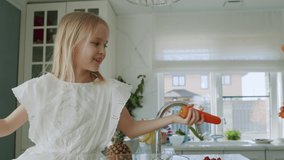 The sisters had a carrot fight. Caucasian children prepare salad and have fun in the kitchen at home . Slow motion 4K UHD video 50 fps