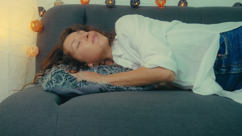 Exhausted young sleepy woman falls down on sofa. Tired lady sleeping on couch at home alone. girl lying asleep feeling lack of motivation | Shutterstock HD Video #1070233192