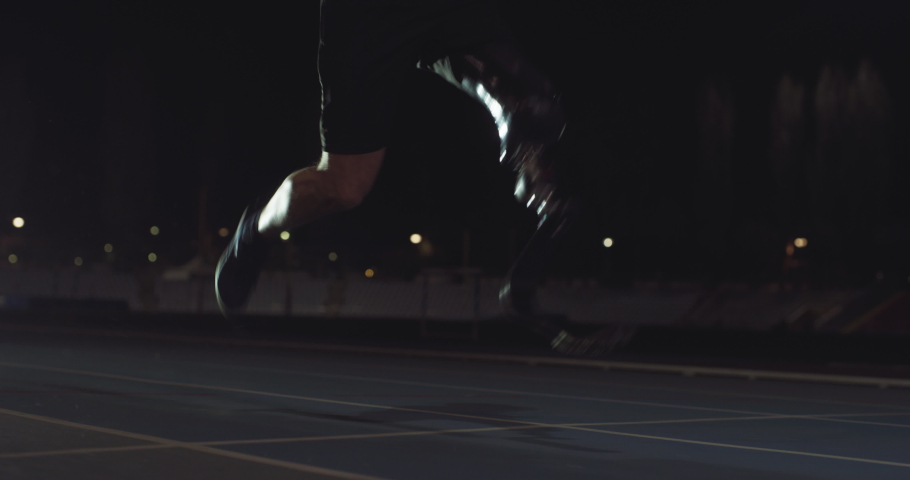 Cinematic close up of disable man with legs prosthesis running with effort with racing auto behind on car track at night. Concept of handicapped people active lifestyle, determination, motivation. Royalty-Free Stock Footage #1070233609