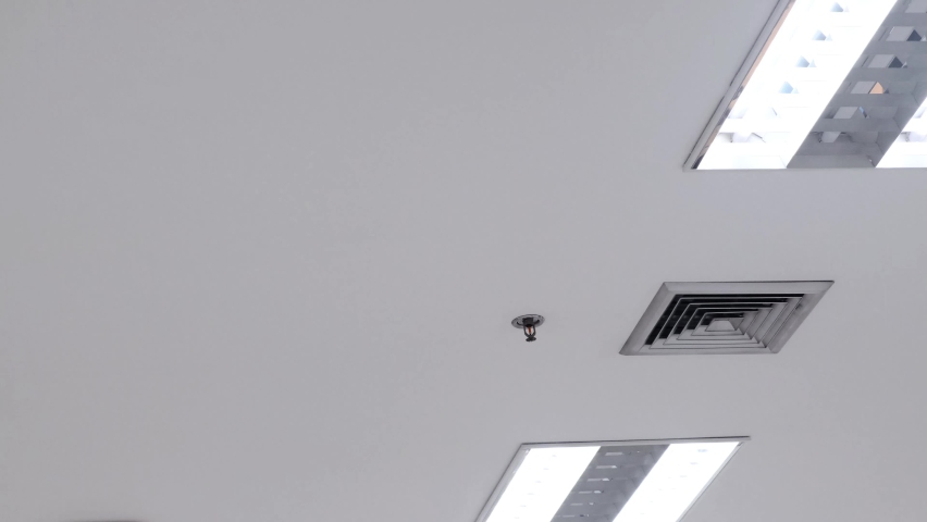 Air vent on a ceiling, pans to air vent cover on office ceiling, Plastic ventilation grid, piece of home ventilation system. Royalty-Free Stock Footage #1070233957