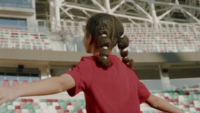 Portrait of African American Black child girl walking onto the field of huge soccer football stadium, spreading hands, dreaming of becoming professional player, soccer star. Women sport concept - Powered by Shutterstock - Get 15% off with code: PIKWIZARD15