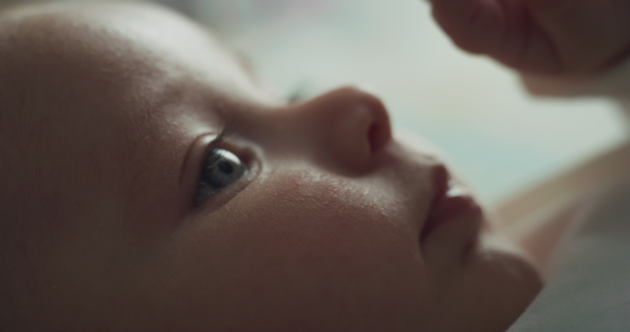 Cinematic authentic macro shot of cute newborn baby boy with blue eyes is looking and smiling in the camera. Concept of children,baby, parenthood, childhood, life, family, future. Royalty-Free Stock Footage #1070235175