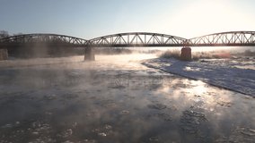 Cinematic Drone Shot, Flies Forward Over the Frozen River and Under Red Steel Bridge at Sunrise, Aerial 4k Footage