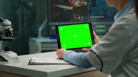 Back view of chemist woman holding tablet with green mockup in modern equipped lab. Team of microbiologists doing vaccine research writing on device with chroma key, isolated display. - Powered by Shutterstock - Get 15% off with code: PIKWIZARD15