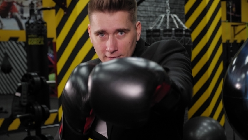 Close-up of a successful serious businessman in boxing gloves boxing in the ring