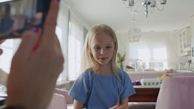 Girl dancing while mother films her with a smartphone camera. Concept for technology use, artistic expression among young people. Young content creation social media. Dance moves, dab floss