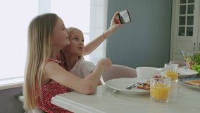 Children take selfies during a delicious breakfast or lunch. Two girls eat toasted bread with chocolate nut butter , fruits and berries. Slow motion 4K UHD video 50 fps