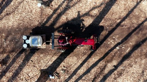 Red Tractor Driving Down Trails Collecting Sap From Maple Trees For Sugar Shack in Quebec Canada to Process into Maple Syrup. 4k Aerial Drone Shot