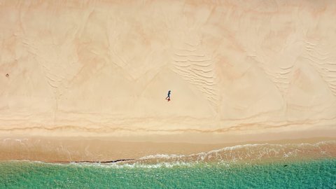 Lingua areia, Portinho da Arrabida, Portugal. Aerial view of a man running within unspoiled beautiful beach. Yellowish dunes steeply falling into the calm waters. High quality 4k footage