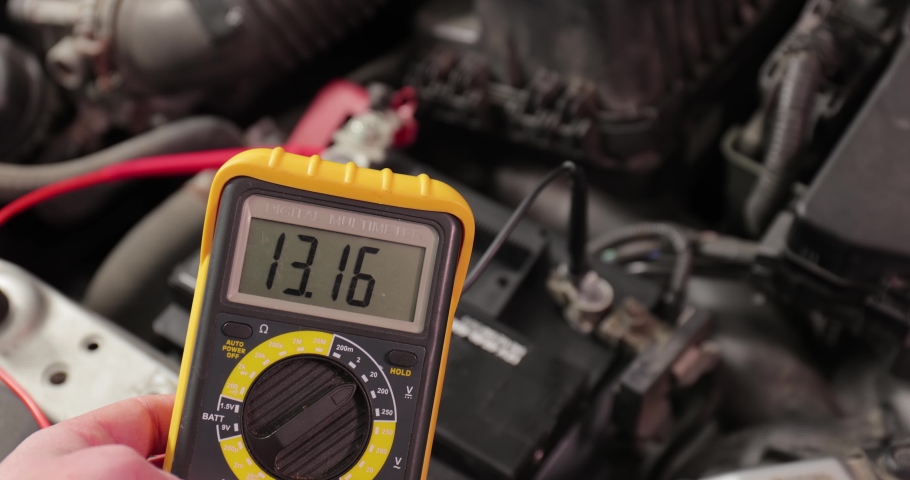 Car starter battery voltage measured with multimeter. Voltage is around 13 volts as the alternator finished recharging the battery. Electric system working well. | Shutterstock HD Video #1070262796