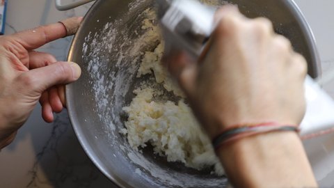 video of a closeup of hands using a mixer to mix cookie dough