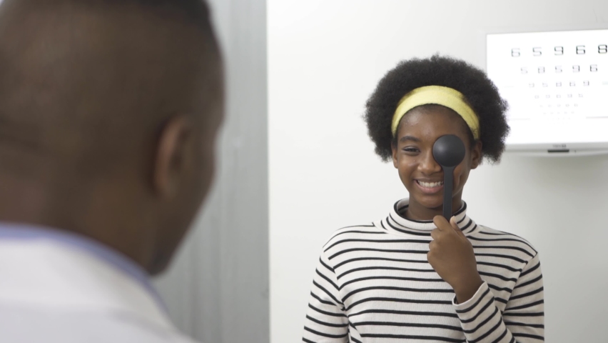 African teen girl reading eye chart during distance vision exam, health concept.