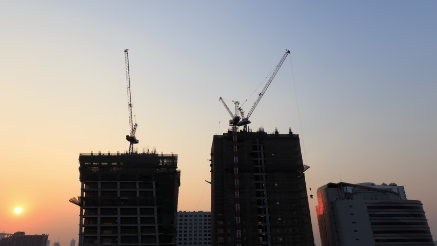 4K Timelapse of sunset over the contruction site with big cranes on top of the building