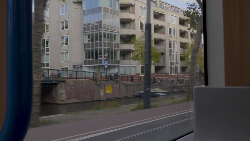 Looking through window of tram moving along river in Amsterdam.