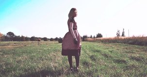 The girl in the field, the dress in polka dots swaying in the wind. Bright overexposed video, the effect of the bright sun. Styling video. Selective focus, 4K.