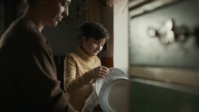 Poor mature mother and small daughter washing dishes indoors at home, poverty concept. - Powered by Shutterstock - Get 15% off with code: PIKWIZARD15