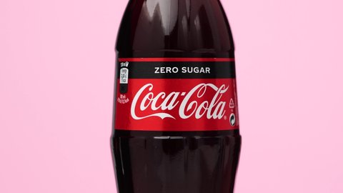 Estonia, Tallinn - March 2021: glass bottle coca-cola zero sugar drink rotating on isolated pink background. Sparkling coca-cola soda rotating 360 degree, closeup wit copy space