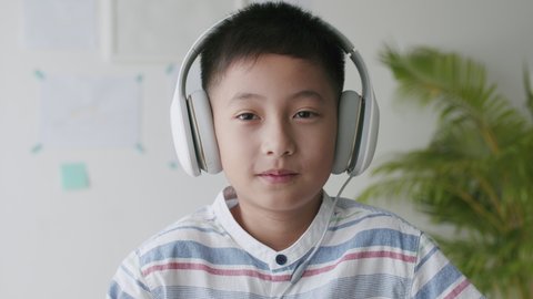 Happy Asian little boy smile on the face, Asia child feeling wear a headphone at home morning. Portrait of a kid looking to camera