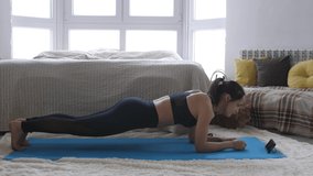 Young woman in sportswear doing workout, aerobics sport fit at home while Maine Coon cat is sitting side by side in room.