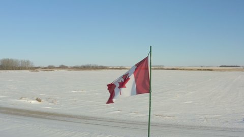 Canadian Flag Blowing in the wind at the frozen Canadian winter prairie