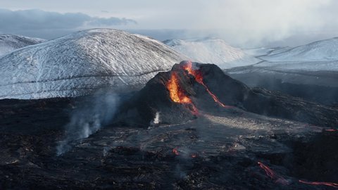 Aerial at active volcano in Iceland valley spewing lava, spatter cone