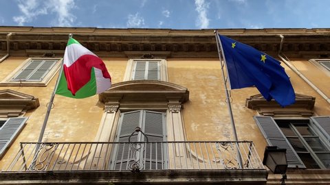 The flags of Italy and the European union flying on the balcony of a public building in Rome. Politics and economics.