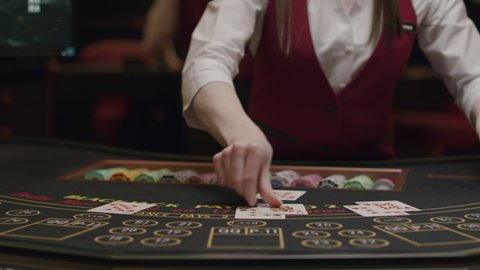 Croupier behind gambling table in a casino. Dealer shuffles the cards. Nightlife