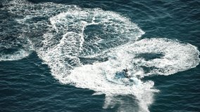Aerial drone video of watercraft scooter making extreme manoeuvres, while cruising in high speed over deep blue open sea ocean