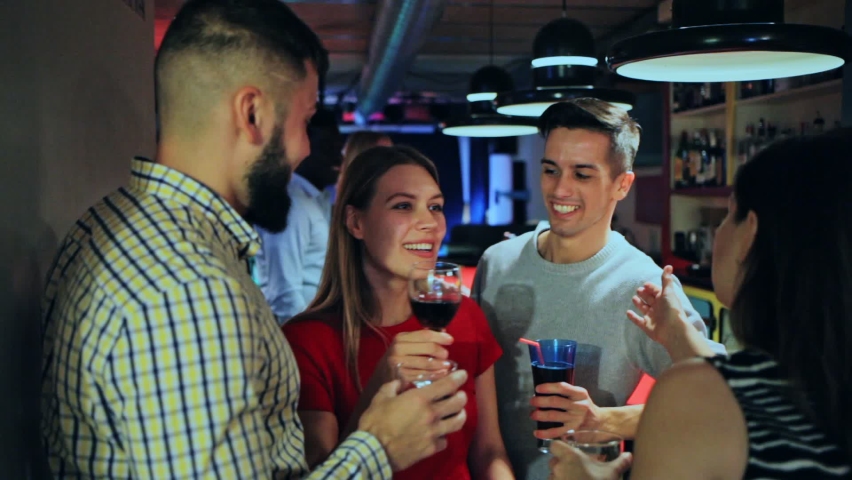 Group of friends clinking glasses with cocktails at night club 