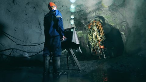 Underground development, underground extraction, underground mining operations. Boring machine is getting managed by a mine worker
