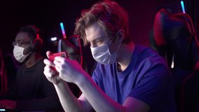 At the computer club, a cute guy in a medical mask plays a game through an app on his smartphone